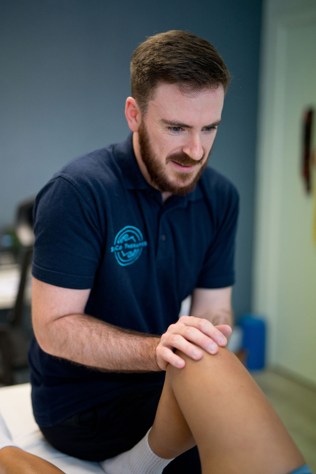 Sports therapist assessing a patient's knee at SoCo Therapies in Bournemouth