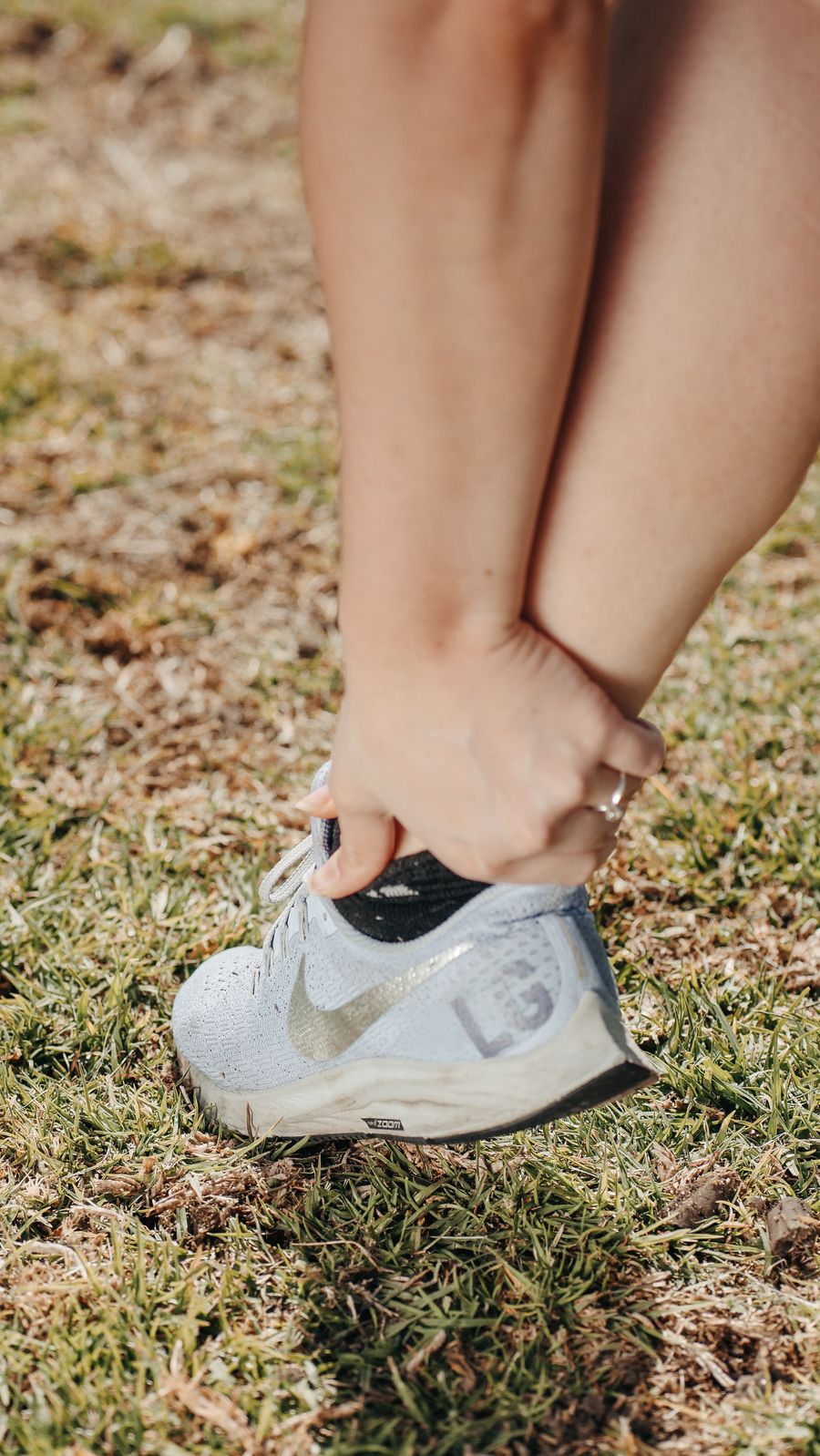 Person holding their ankle and foot while wearing a running shoe
