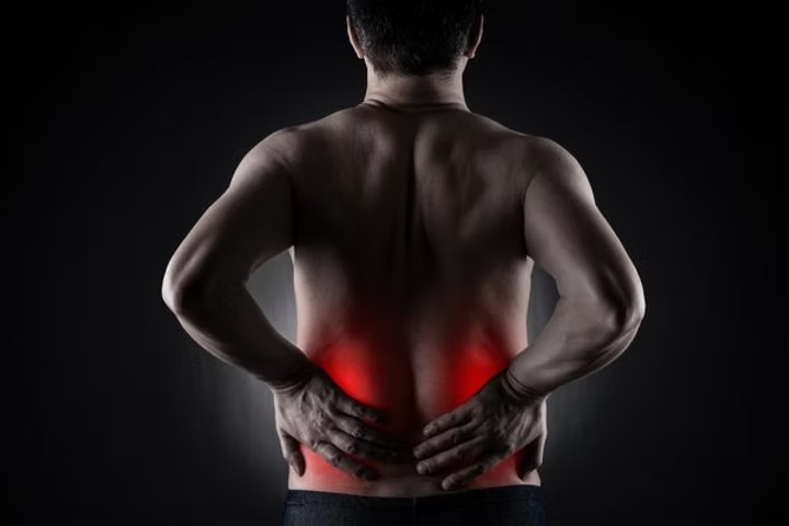 Person holding their lower back with red areas highlighting sciatica pain