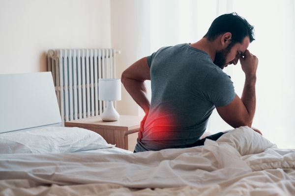 Person resting with lower back pain while reading about home remedies for sciatica